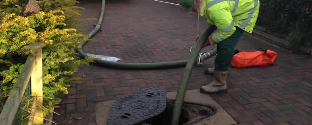 Septic tank cleaning technician servicing a septic tank with a vacuum hose in Brandon, FL
