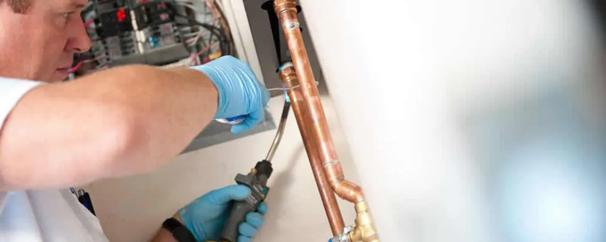 Water heater repair technician testing copper pipe connections and controls in Brandon, FL