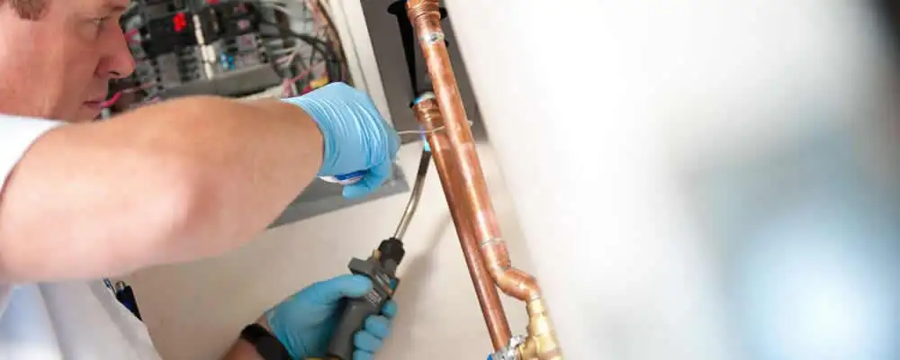 Water heater repair technician testing copper pipe connections and controls in Brandon, FL